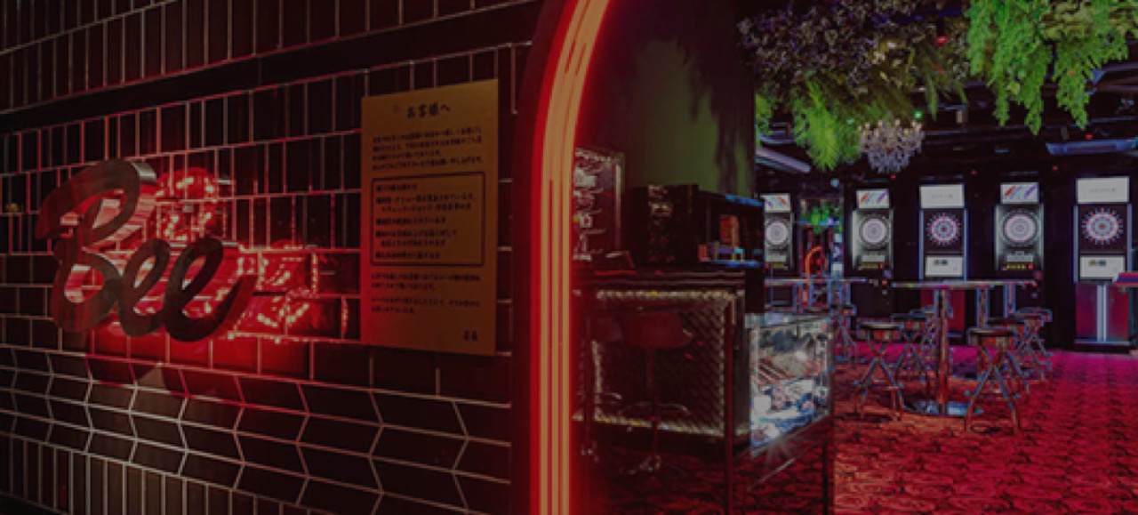ダイニングダーツバー Bee 池袋店のネオンサインとダーツマシン・ラウンジ席が広がる店内