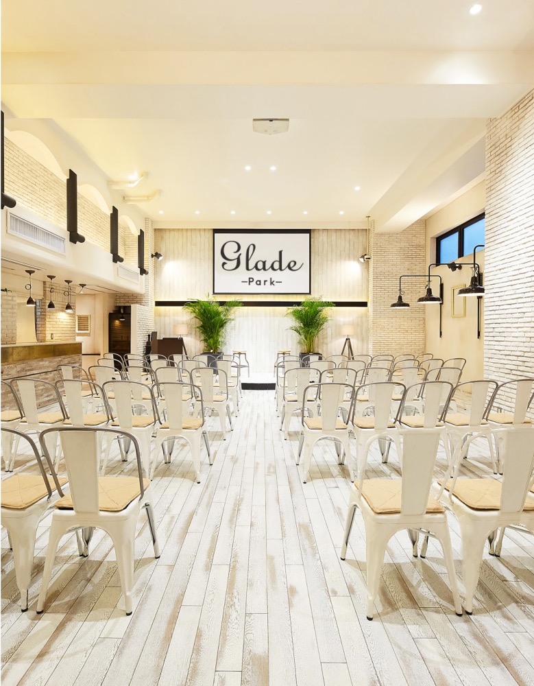 GLADE PARK 恵比寿の大広間。白基調の明るい会場に白いチェアがシアター形式で並び、奥壁に「Glade Park」ロゴサイン